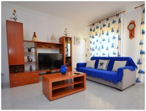 a living room with a blue couch and a tv at Apartamentos Capitolina in Quarteira