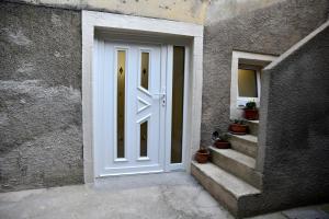 a white door in a stone building with stairs at Apartman Marko Cres in Cres