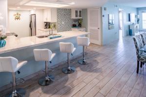 a kitchen with wooden floors and white bar stools at Saida in South Padre Island