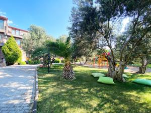 un parque con 2 palmeras y un parque infantil en Assos Park Hotel, en Behramkale