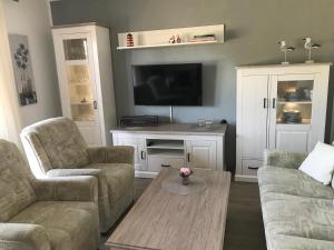 ein Wohnzimmer mit zwei Sofas und einem Fernseher in der Unterkunft Ferienwohnung "Sielblick" in Dornumersiel in Dornum