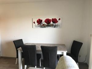 einen Esstisch mit Stühlen und ein Gemälde von roten Blumen in der Unterkunft Ferienwohnung "Sielblick" in Dornumersiel in Dornum