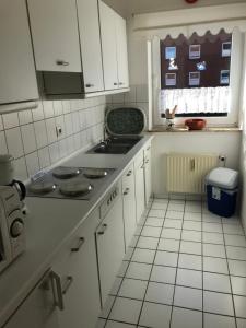 eine Küche mit weißen Schränken und einem Herd mit Backofen in der Unterkunft Ferienwohnung "Sielblick" in Dornumersiel in Dornum