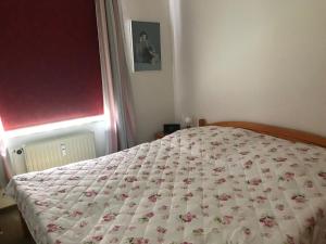 ein Schlafzimmer mit einem Bett mit geblümter Tagesdecke in der Unterkunft Ferienwohnung "Sielblick" in Dornumersiel in Dornum
