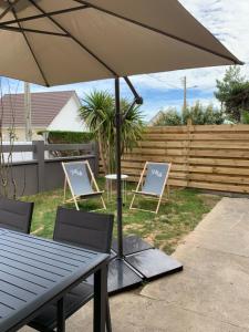 une table, deux chaises et un parasol dans l'établissement La Maison de Juliette, à Agon-Coutainville