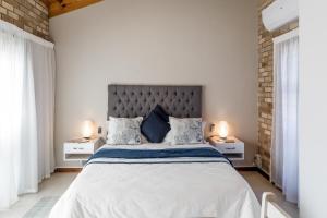 a white bedroom with a large bed with two night stands at Wagtails Guest House in Port Elizabeth