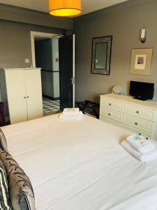 a bedroom with a large white bed and a dresser at The Traxx Hotel in Bangor