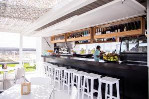 bar z białymi stołkami i mężczyzna stojący przy ladzie w obiekcie Carlito HolidayFV w Corralejo