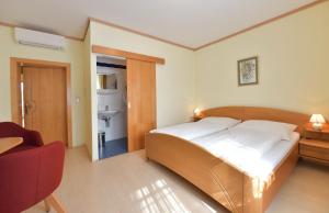 een slaapkamer met een groot bed en een rode stoel bij Blumenhof Wegleitner in Illmitz