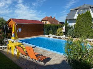 ボニャルツバシュにあるSárga-Kék házのオレンジ色の椅子と黄色のパラソルが備わるスイミングプールを併設しています。