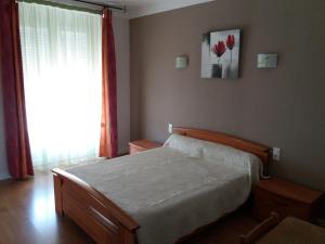 een slaapkamer met een bed en een raam met rode bloemen bij Gîte "les hortensias" au coeur de Lacaune in Lacaune