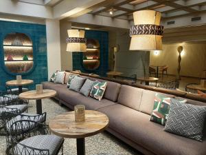 vestíbulo con sofá, mesas y sillas en Hotel Corona de Castilla Burgos en Burgos