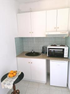 La cuisine est équipée de placards blancs et d'un four micro-ondes. dans l'établissement George Michalas (Vivaria Apartments), à Paleokastritsa