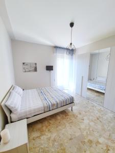 a white bedroom with a bed and a mirror at Affittacamere Zona Caserma-Stazione in Foligno