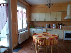 een keuken met een tafel en stoelen en een keuken met witte kasten bij Gîte "les hortensias" au coeur de Lacaune in Lacaune
