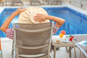a woman sitting in a chair in front of a pool at Luxury Apartments Queen in Petrovac na Moru