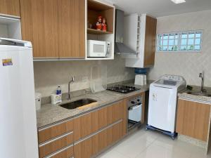 eine Küche mit Holzschränken und einem weißen Kühlschrank in der Unterkunft Condomínio Solar Porto Rico AP 3 in Porto De Galinhas