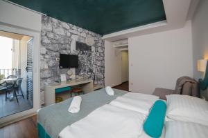 ein Schlafzimmer mit einem großen Bett und einer Steinmauer in der Unterkunft Hotel Ivando in Drvenik