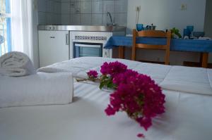 a white bed with a bouquet of purple flowers on it at Armenaki Apartments in Sampatiki