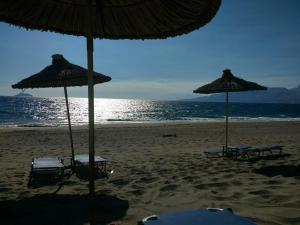 two umbrellas and chairs on a beach with the ocean at Nefeli in Kalamaki