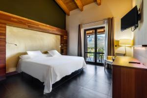 a bedroom with a bed and a desk and a television at Hotel Spa Aguas de los Mallos in Murillo de Gállego