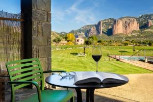 a glass of wine sitting on a table with a book at Hotel Spa Aguas de los Mallos in Murillo de Gállego