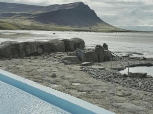 a body of water with rocks and a mountain at Móra guesthouse in Birkimelur 