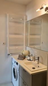 a bathroom with a sink and a washing machine at APARTAMENT WILKASY II (k. Giżycka ) in Wilkasy