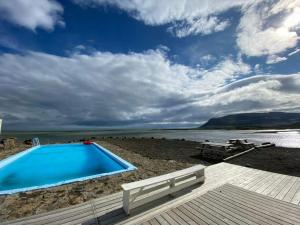 a swimming pool on a beach next to a body of water at Móra guesthouse in Birkimelur 