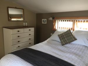 1 Schlafzimmer mit 2 Betten und einer Kommode mit einem Spiegel in der Unterkunft Applegrove B&B in Boat of Garten