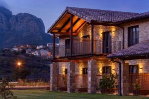 a stone house with a balcony and mountains in the background at Hotel Spa Aguas de los Mallos in Murillo de Gállego