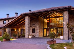 a large brick building with large glass doors at Hotel Spa Aguas de los Mallos in Murillo de Gállego