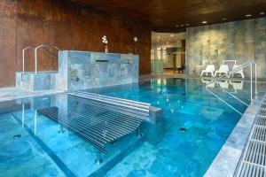 a large pool with blue water in a building at Hotel Spa Aguas de los Mallos in Murillo de Gállego