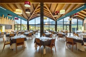 a dining room with tables and chairs and large windows at Hotel Spa Aguas de los Mallos in Murillo de Gállego