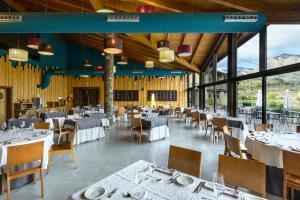 a dining room with tables and chairs and large windows at Hotel Spa Aguas de los Mallos in Murillo de Gállego