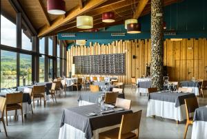 a dining room with tables and chairs and windows at Hotel Spa Aguas de los Mallos in Murillo de Gállego