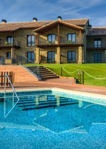 a house with a swimming pool in front of a house at Hotel Spa Aguas de los Mallos in Murillo de Gállego