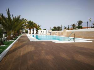 einen Pool mit Holzboden und Palmen in der Unterkunft Dunasol in Corralejo + 16 Fotos