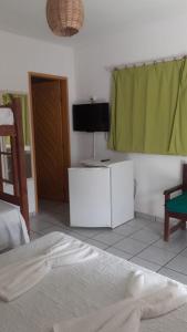 a bedroom with a bed and a flat screen tv at Pousada Pé na Areia in Pipa