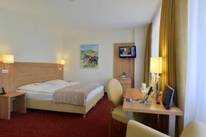レマーゲンにあるRinghotel Haus Oberwinterのベッド、デスク、テレビが備わるホテルルームです。