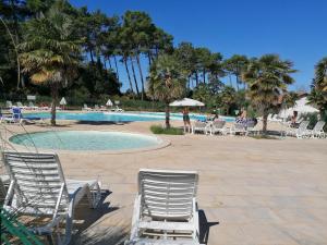 a pool with chairs and tables and palm trees at T2 Antigua Ondres plage avec piscine et tennis in Ondres