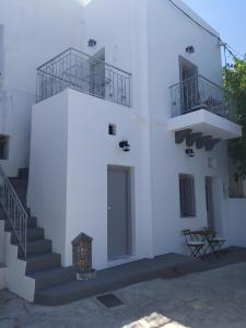 ein weißes Gebäude mit einer Treppe und einer Tür in der Unterkunft Melikarou houses in Skyros