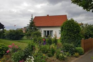 a white house with a red roof and some flowers at Ferienwohnung Ina in Michelau