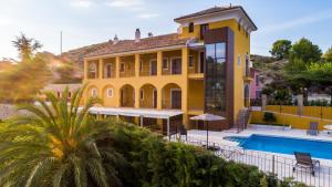 una casa amarilla con una piscina frente a ella en Hotel Rural El Molino de Felipe, en Mula