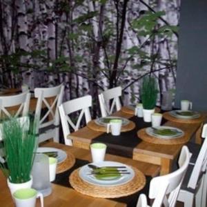 a wooden table with white chairs and plates of food at Leśna Villa in Wiśniówka Mała