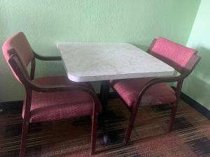 a table with two pink chairs and a white marble table and chairs at Seminole Inn in Donalsonville