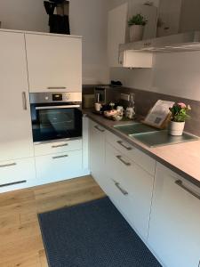 a kitchen with white cabinets and a stove top oven at BeeHome Euskirchen in Euskirchen