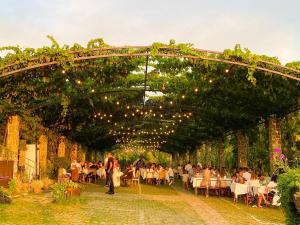 a group of people sitting at tables under an arch with lights at Mrizi i Zanave Agroturizëm in Lezhë