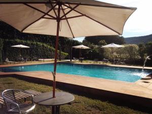 a table with an umbrella next to a swimming pool at Serranos Park Hotel in Paraíso do Tocantins