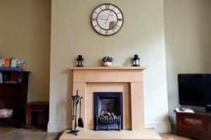 a clock on a wall above a fireplace at Bronte Railway Cottage at Haworth in Haworth